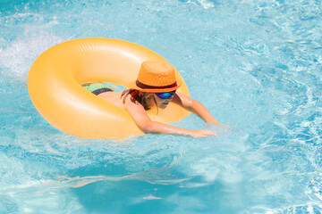 Child playing in swimming pool. Kids holidays and vacation concept. Summer kids cocktail. Happy little boy with inflatable ring in swimming pool.
