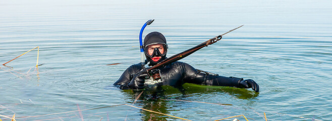 Spearfishing, men in a neoprene wetsuit in a lake with weapons for spearfishing, a harpoon diver. Underwater hunting and fishing. 