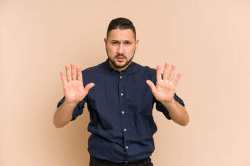 Adult latin man cut out isolated standing with outstretched hand showing stop sign, preventing you.