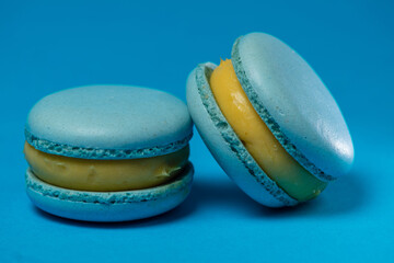 two blue makaruns on a blue background. air dessert with blueberries