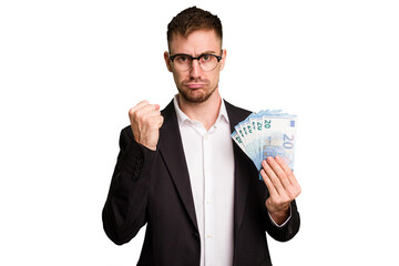 Young business caucasian man holding euro banknotes isolated cut out showing fist to camera, aggressive facial expression.