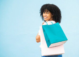 Back, portrait and black woman with bags, shopping and purchase expensive items with girl on blue studio background. Mockup, Jamaican female and customer with boutique clothes, retail and discount