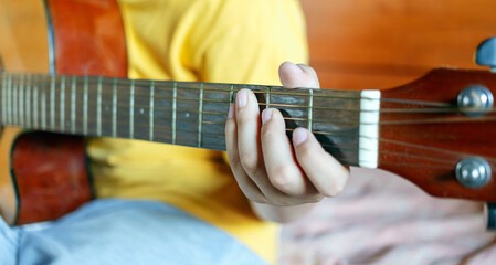 Close-up of white boy's hands holding guitar chords