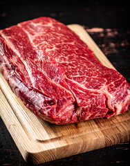 A piece of fresh raw beef on a cutting board. 