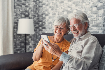 Elderly grandfather and grandmother spend time having fun using smartphone apps, middle-aged wife enjoy online entertainments, taking selfie with old husband, older generation and modern tech concept.