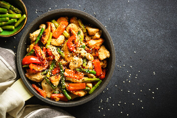 Chicken stir fry with vegetables at stone background. Top view with copy space.