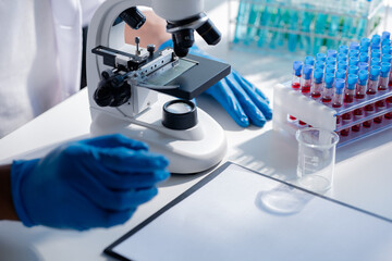 Lab assistant, a medical scientist, a chemistry researcher holds a glass tube through the blood sample, does a chemical experiment and examines a patient's blood sample. Medicine and research concept.
