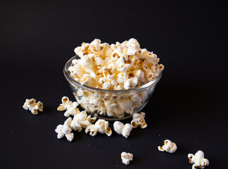 A popcorn-filled glass bowl, standing out against a dark and empty background