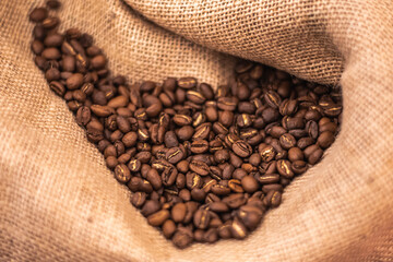 Roasted brown coffee beans or seeds in a jute sack, close up