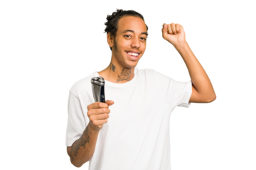 Young African American man holding a razor isolated raising fist after a victory, winner concept.