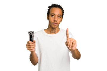 Young African American man holding a razor isolated showing number one with finger.