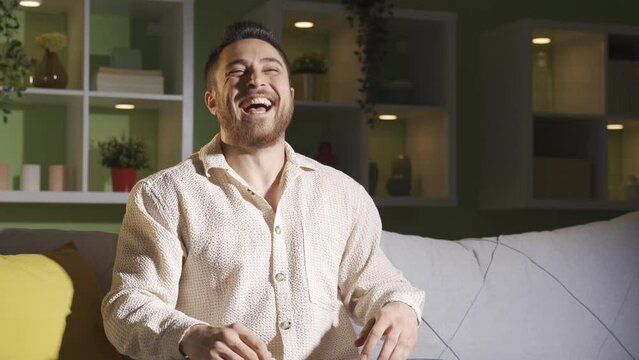 Man with schizophrenia sitting alone at home. Mentally ill man
The madman sitting alone in the living room hallucinates and starts laughing at himself.
