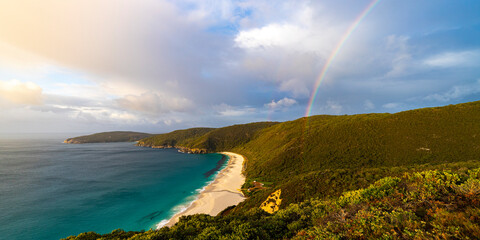 a panorama of the famous shelly beach in west cape howe national park with a rainbow at sunset; a...
