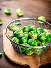 Brussel cabbage in a colander on a cutting board. 