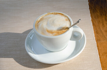 Cup of coffee in a white cup on wooden table background. Top view.