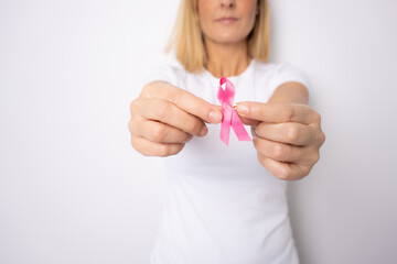 Young beautiful blonde woman holding pink cancer ribbon symbol with serious face pointing hand to herself
