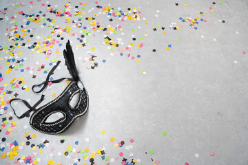 Venezianische Karnevalsmaske auf grauem Hintergrund mit bunten Konfetti