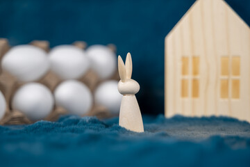 petit lapin en bois dans un décor de bois et de fourrure avec des oeufs de pâques à décorer