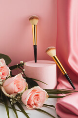 Beauty cosmetic makeup product layout. Fashion woman makeup brush, powder. Modern pink aesthetic composition with bouquet of pink rose flowers and pastel pink silk curtain.