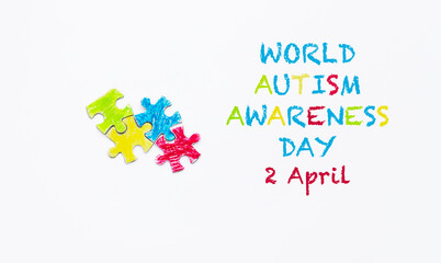 World Autism awareness day 2 April text. White background. Puzzles and text painted with crayons.