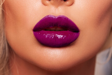 Close-up Beautiful woman lips. makeup. Lip glossy lipstick. Sexy lips. Part of face, young woman close up. cherry or purple color lipstick on large lips. Perfect beautiful makeup.  