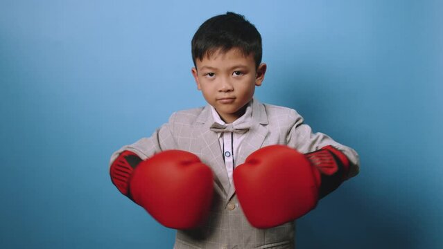 the studio shot isolated image of the boy wearing the boxing gloves with the blue backdrop