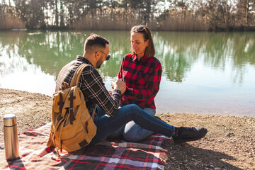 Loving couple on the lake. A young man and woman are sitting on a blanket by the lake. Young family...