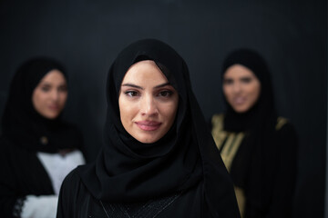 Group portrait of beautiful Muslim women in a fashionable dress with hijab isolated on black background