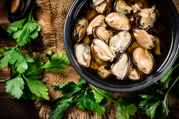 Pickled mussels in a bowl with parsley on burlap. 