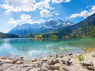 rocky bathing beach at lake shore Eibsee, view to Zugspitze mountain, upper bavarian summer...