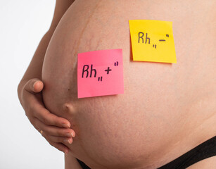 Stickers on the belly of a pregnant girl with inscriptions negative and positive Rh factor. Rh...