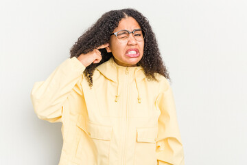 Young african american woman isolated on white background covering ears with fingers, stressed and desperate by a loudly ambient.
