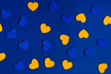 Fototapeta na wymiar Yellow and blue hearts on blue background. Abstract composition with the colors of Ukrainian flag