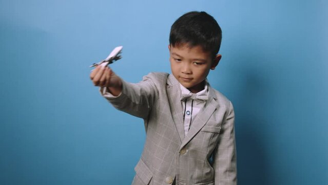 the studio shot isolated image of the boy playing the miniture airplane with the blue backdrop