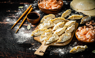 Raw dumplings gyoza with shrimp on a cutting board. 