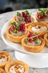 Tartlets stuffed with codfish liver, codfish caviar and microgreens. Traditional cold portioned appetizer in a pastry basket.