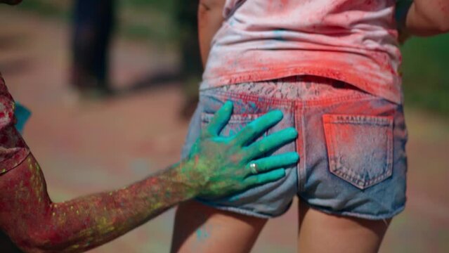 View of the buttocks of a girl who is slapped by a guy's hand stained with paint