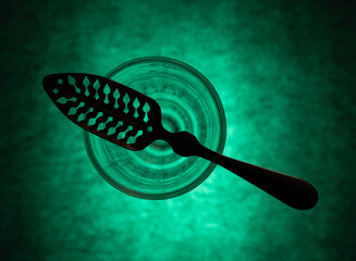 Traditional slotted absinthe spoon on the top of absinthe glass, flat lay, selective focus
