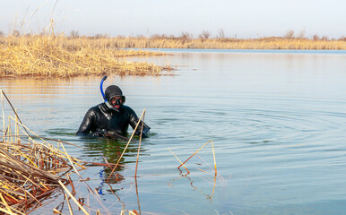 The diver swims in a wetsuit, flippers and a mask with a tube. The rescuer divers carries out work...