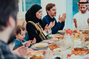 Fototapeta na wymiar A Muslim family praying together, the Muslim prayer after breaking the fast in the Islamic holy month of Ramadan