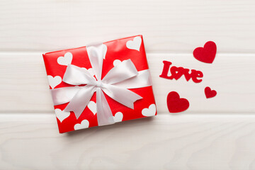 Gift box with hearts on wooden background, top view