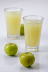 Indian gooseberry or amla fruit and juice having detox properties served in small glasses.