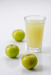Indian gooseberry or amla fruit and juice having detox properties served in small glasses.