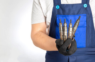 Car mechanic holds fuel car injectors in his hand. The concept of replacing and tuning the fuel system of a car at a car service. Copy space for text