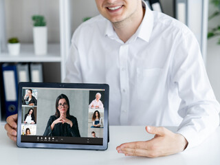 Video meeting. Digital briefing. Distant communication. Cheerful man showing business team working on tablet screen at office workplace.
