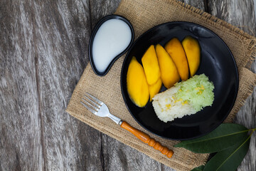 Sticky rice mango thai dessert on banana leaf wood texture top view.
