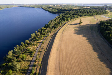 view of the lake, field and bicycle road at sunset from the drone