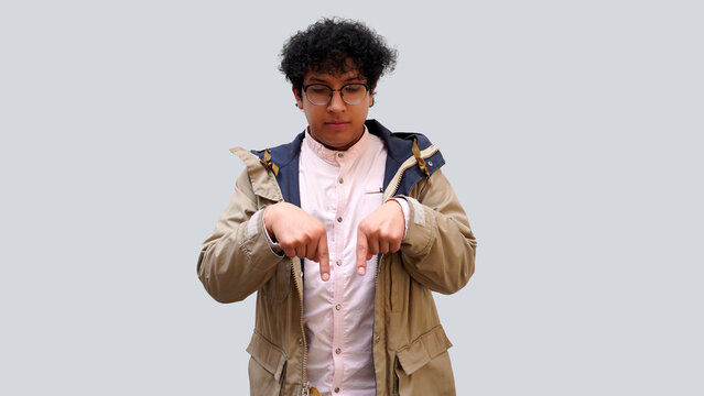Joven latino cabello rizado con lentes apuntando hacia abajo