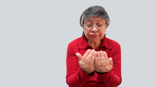 Mujer mayor latina observa sus manos