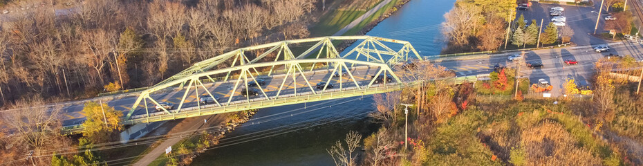 Panorama aerial view truss bridge with car traffic over Erie Canal colorful fall foliage in afternoon light Pittsford, New York